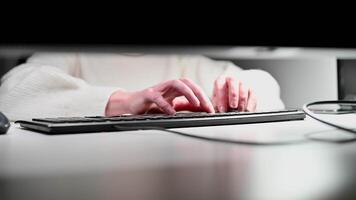 Close-up of hands typing on keyboard in a modern office workspace with soft lighting ambiance video