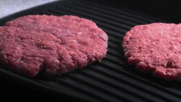 Close-up of raw burger patties sizzling on an indoor grill in a modern kitchen setting video