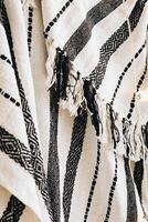 Handwoven textile featuring geometric patterns and fringed edges displayed in a cozy setting photo
