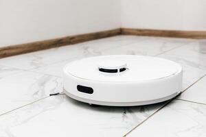 Robotic vacuum cleaner operating on tiled floor in modern home environment photo
