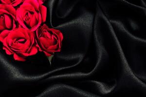 Red roses arranged on elegant black fabric create a striking and romantic display photo
