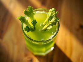 A glass of fresh celery juice with celery garnish on a wooden table photo