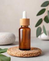 A bottle of essential oil is on a wooden plate with a green leaf and a stone photo