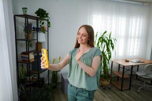 Smiling woman waving at friends during a virtual call at home photo