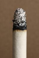 Extreme close-up of a cigarette with a tall column of ash against a neutral background photo