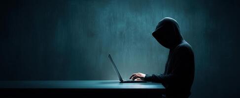 The Hacker Working Stealthily at a Laptop in a Dimly Lit Environment photo