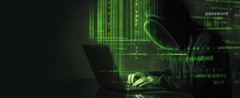 The hacker typing on a laptop illuminated by glowing green code. photo