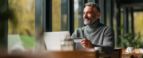 The man enjoying a coffee while browsing on his laptop at a cafe. photo