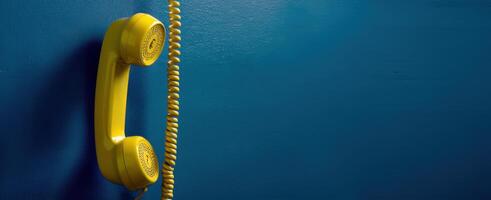 The vintage yellow telephone receiver against a vibrant blue wall backdrop photo
