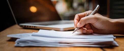 The hand writing on documents with a laptop in a modern workspace. photo