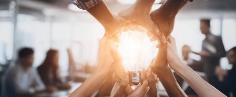 The hands joining together to support the illuminated lightbulb of creativity. photo
