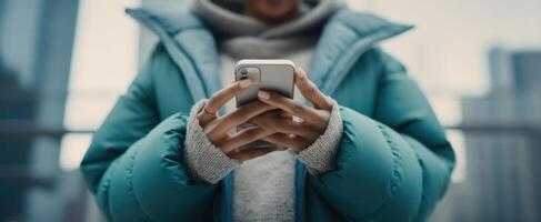 The person in a stylish puffer jacket using a smartphone in an urban setting. photo