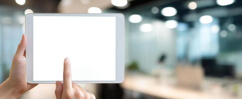 The tablet held in hands displaying a blank screen in a modern office environment. photo