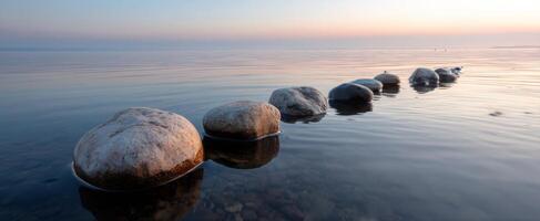 The serene stones create a tranquil pathway across calm waters at sunset. photo