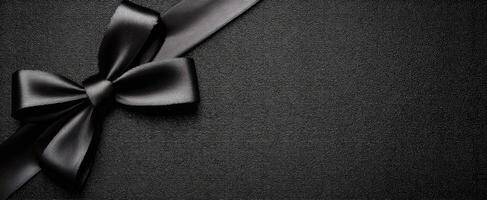 The elegant black ribbon bow on a dark textured background. photo