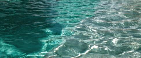 The shimmering surface of crystal-clear turquoise water in a serene environment. photo
