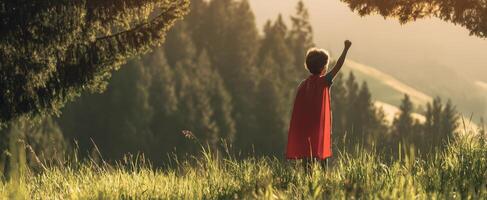The child in a red cape stands triumphantly in nature. photo