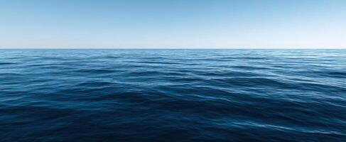 The vast ocean under a clear blue sky with gentle waves. photo