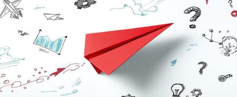 The red paper airplane soaring through a creative doodle-filled environment. photo