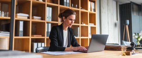 The diligent woman working on a laptop in a modern office setting. photo