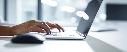 The person typing on a laptop in a modern office workspace. photo