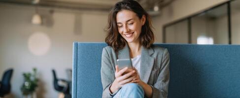 The young woman smiling while using her smartphone in a modern workspace. photo