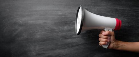 The megaphone held by a hand for making impactful announcements and communication. photo
