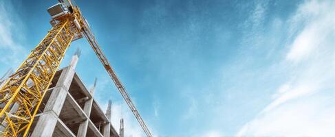 The construction crane towering over a developing urban building site against a bright sky. photo