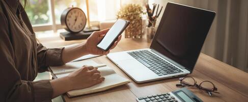 The modern workspace featuring a laptop, smartphone, and notebook on a wooden desk. photo