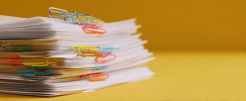 The vibrant stack of paper with colorful paper clips on a yellow background. photo