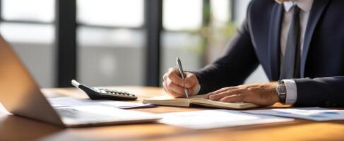 The businessman writing notes at a modern office desk with laptop. photo