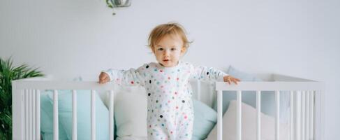 The adorable toddler standing in a cozy nursery filled with pastel colors. photo