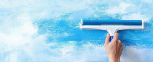 The hand using a paint roller on a blue textured wall photo