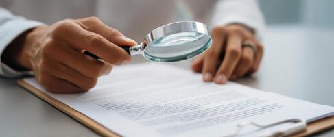 The magnifying glass held by a person analyzing important documents on a desk. photo