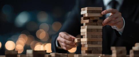 The businessman skillfully builds a wooden block tower amidst evening lights. photo