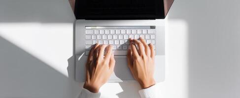 The person typing on a laptop in a bright and modern workspace. photo