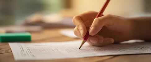 The hand actively writing on an assessment paper with a pencil. photo