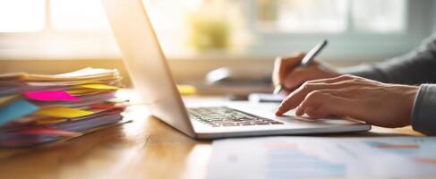 The focused hands working on a laptop with documents in a bright workspace photo