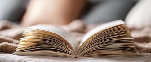 The open book resting on a cozy bed with soft blankets and pillows. photo