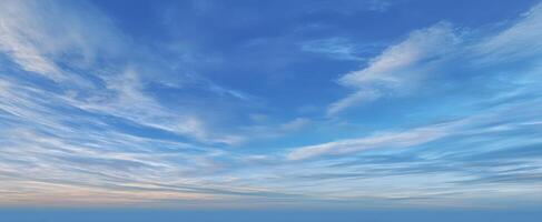 The expansive blue sky with soft clouds at sunset over a tranquil landscape. photo