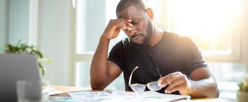 The man experiencing stress while working at his desk in natural light. photo