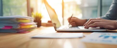 The laptop and documents on a modern workspace desk bathed in sunlight. photo