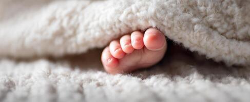 The adorable little foot peeking out from under a fluffy blanket. photo