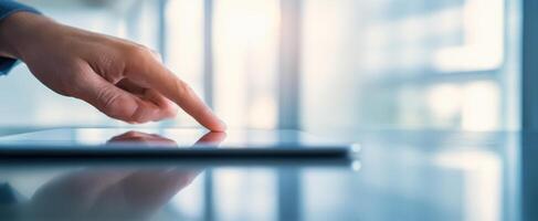 The hand interacting with a sleek tablet in a modern office environment photo