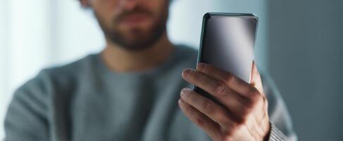 The man interacting with a modern smartphone in a casual indoor setting. photo