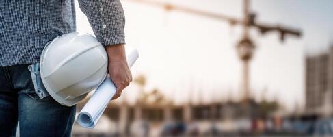 The construction worker holding blueprints on a busy construction site. photo