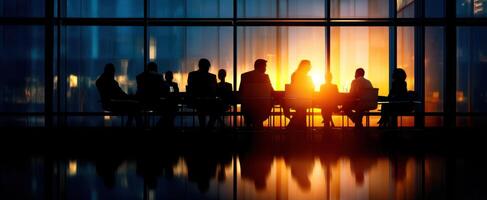 The silhouettes of business professionals in a sunset meeting within a modern office. photo
