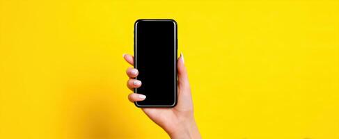 The smartphone held in hand against a vibrant yellow background photo