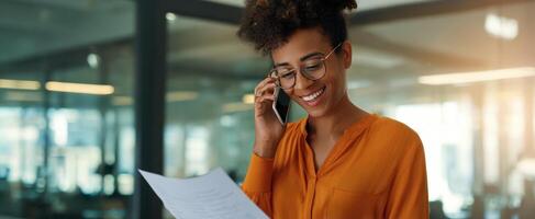 The smiling woman engaged in a phone conversation while reviewing important documents. photo