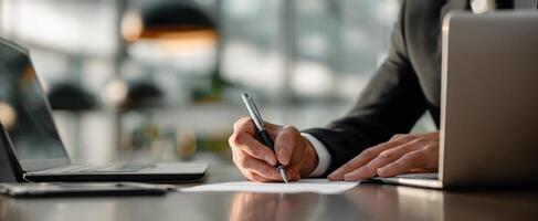The businessman writing on a document while sitting at a modern desk. photo